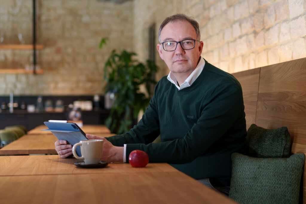 Marc Oliver Thoma am Tisch mit Tablet und Kaffeetasse