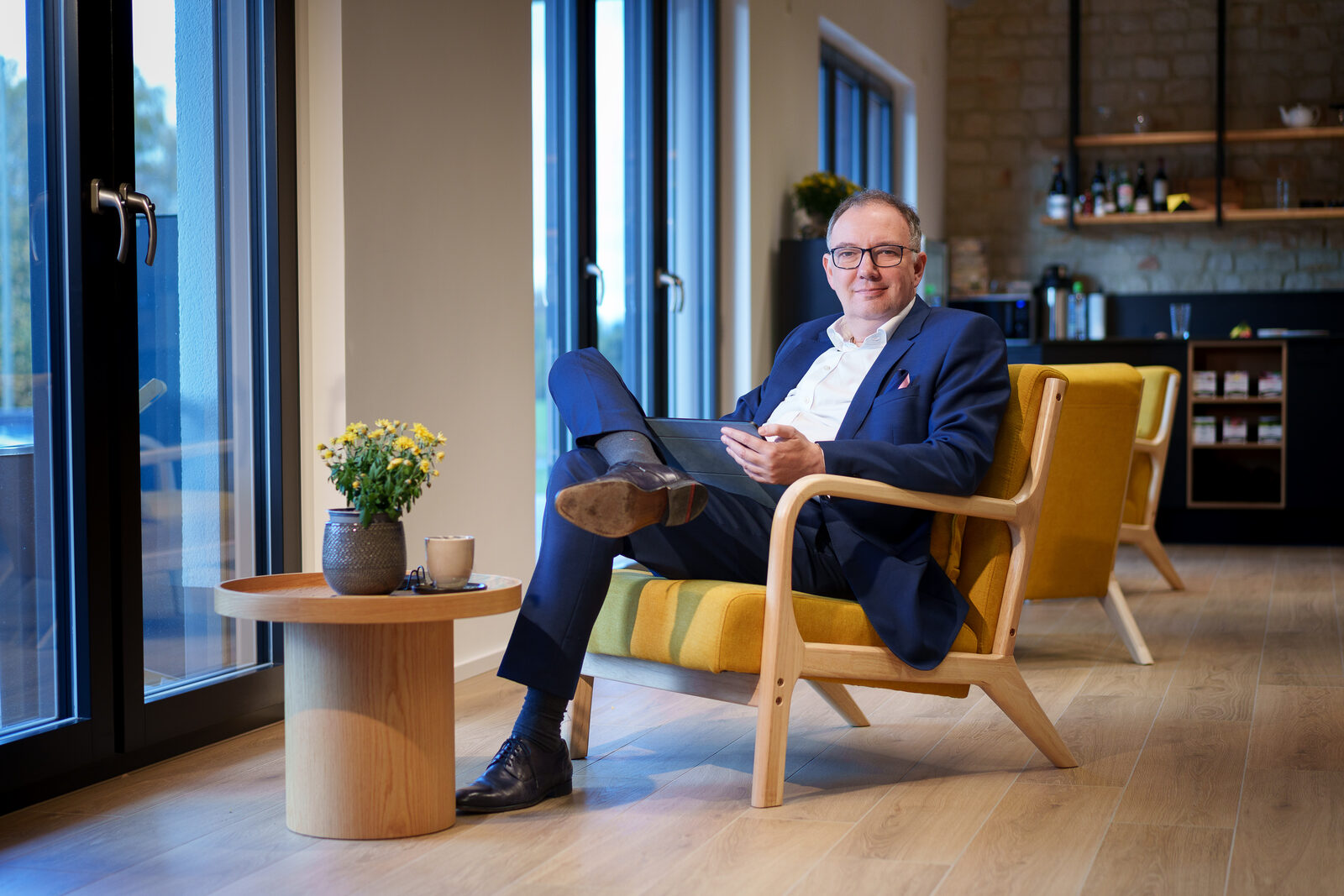 Marc Oliver Thoma im Sessel vor großen Fenstern